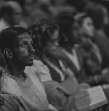 Black and white photo of men and women sitting in an auditorium.