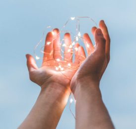 Make a tax deductible donation to Arizona Educates. Depicted image is of a person holding string lights.